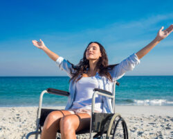 Disabled woman with arms outstretched at the beach on a sunny day